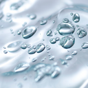 Gotas de agua sobre una superficie con fondo blanco, resaltando la importancia del ácido hialurónico.