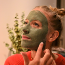Una mujer disfrutando de los beneficios de una mascarilla verde de arcilla purificante contra impurezas en su rostro.