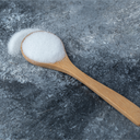 Una cuchara con niacinamida blanca sobre una superficie de concreto. Descubre los beneficios de la niacinamida en tu piel.