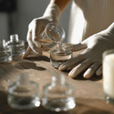 Con delicadeza, una persona de guantes blancos coloca frascos de vidrio sobre una mesa. Creando cosméticos con higiene.