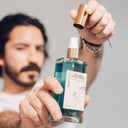 La aplicacion del Limpiador Facial Suave es mediante un dosificador. El envase es de vidrio rectangular.